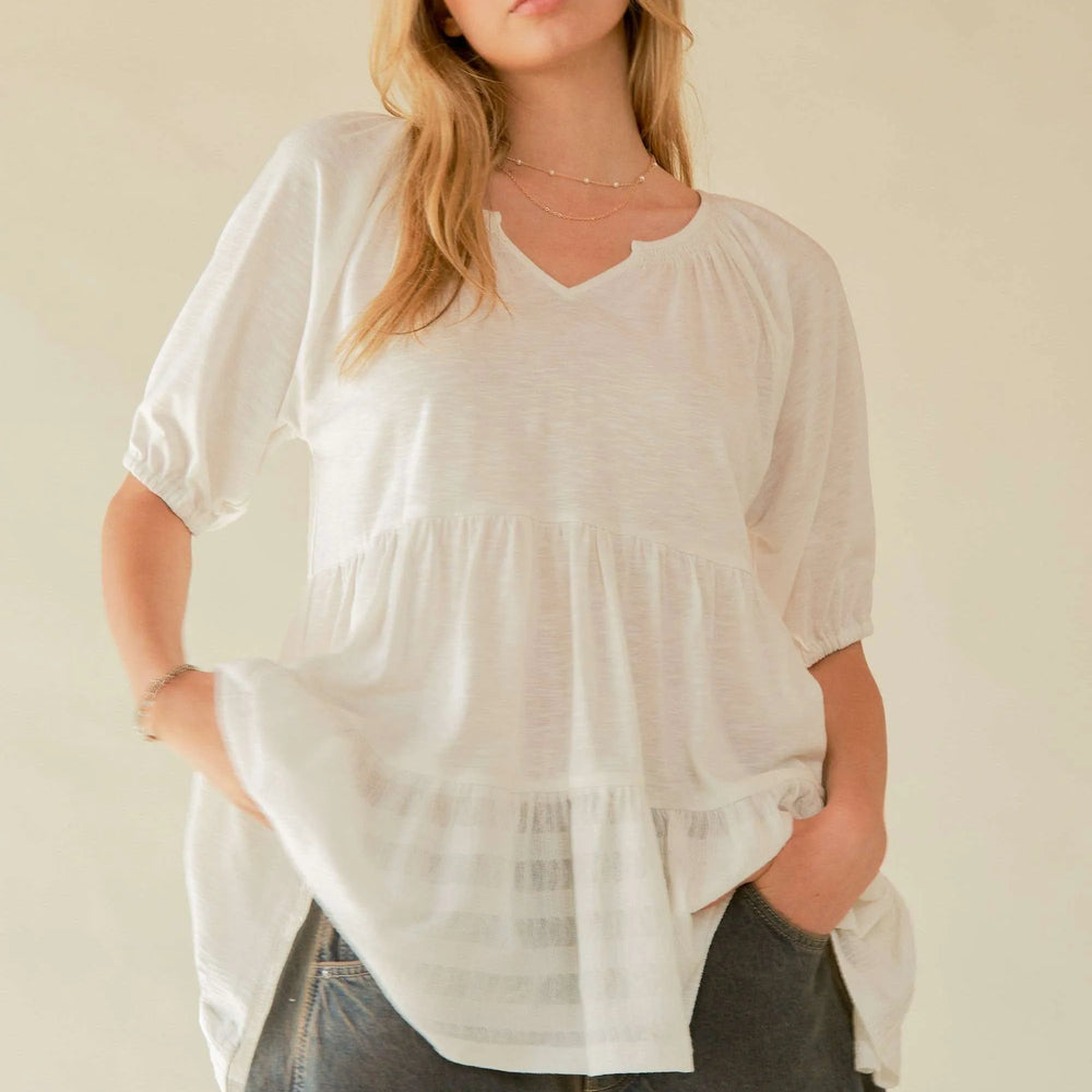 Woman wearing an eco-friendly V-neck tiered blouse from Unique Kulture, featuring lightweight, breathable fabric and a comfortable, flowy design

