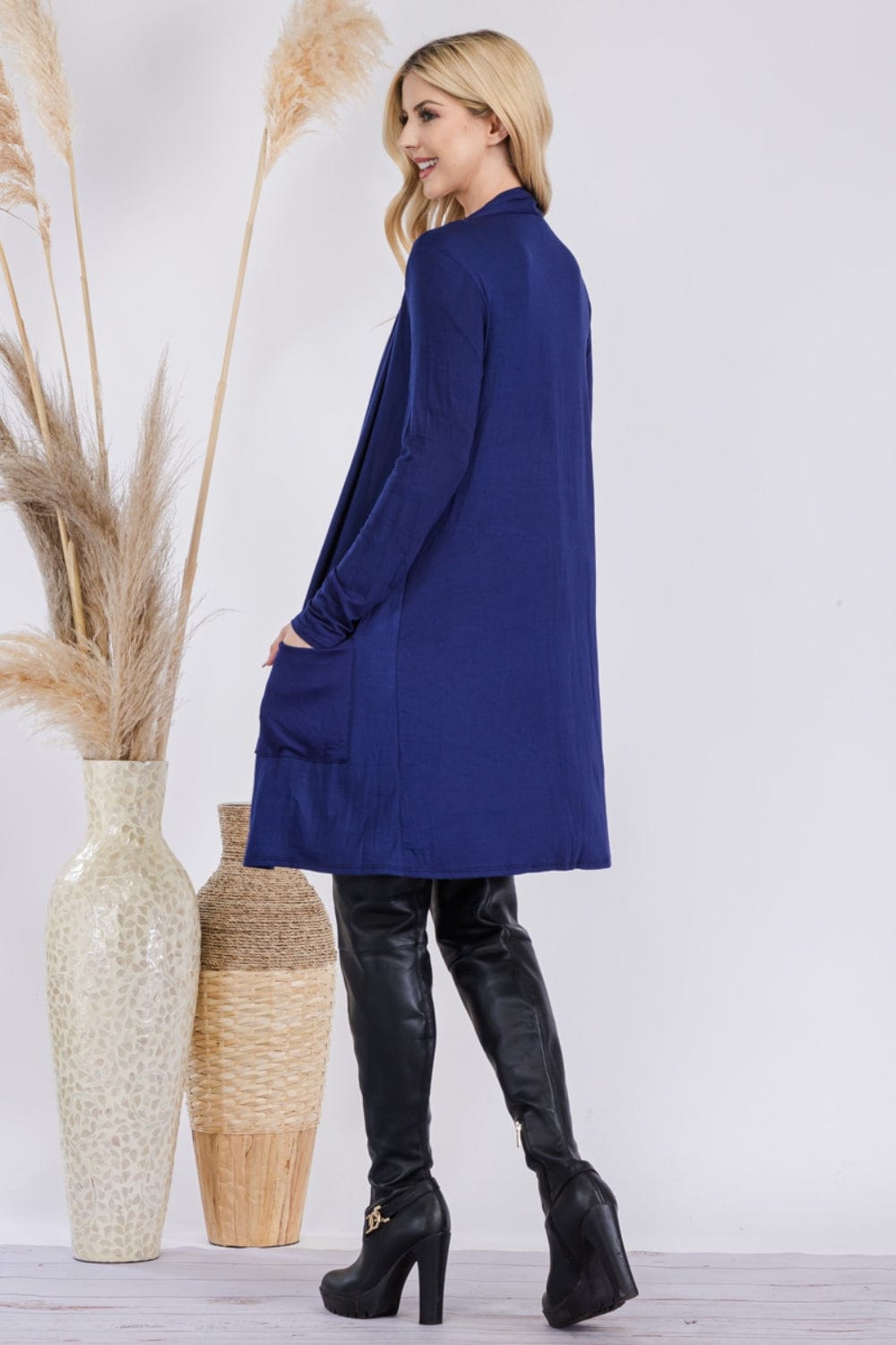  Celeste Full Size Open Front Cardigan with Pockets, featuring a stylish and versatile open-front design in a solid color. The cardigan is made from a highly stretchy fabric blend, showcasing its comfortable fit and functional pockets, perfect for layering over various outfits.
