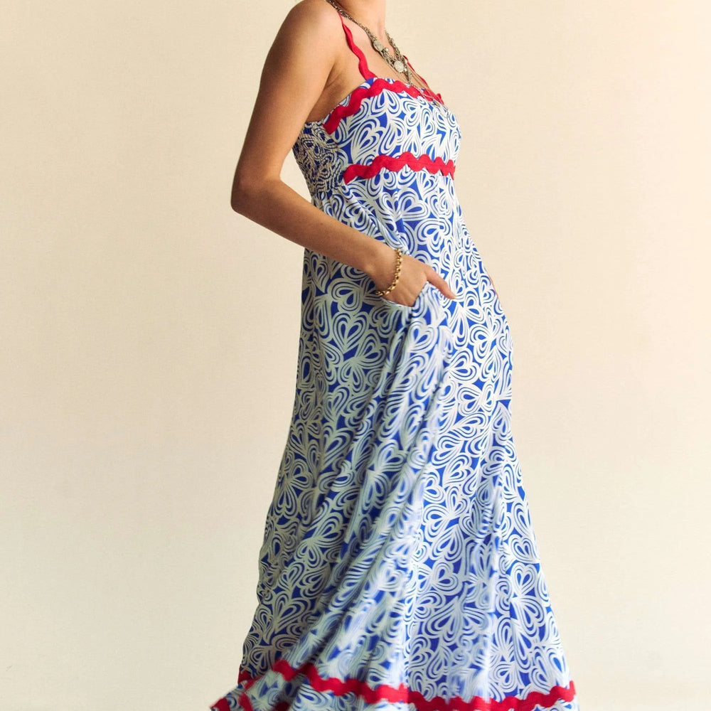 Make a statement with Unique Kulture’s Geo Two-Tone Printed Tiered Maxi Dress with Wavi Trim. This eye-catching maxi dress features a bold geometric two-tone print and playful Wavi trim accents for a touch of boho chic. The tiered silhouette creates beautiful movement, while the slightly stretchy, smocked bodice ensures a flattering and comfortable fit. Crafted from lightweight, breathable polyester, this dress is perfect for special occasions, summer parties, or any day you want to stand out in effortless 