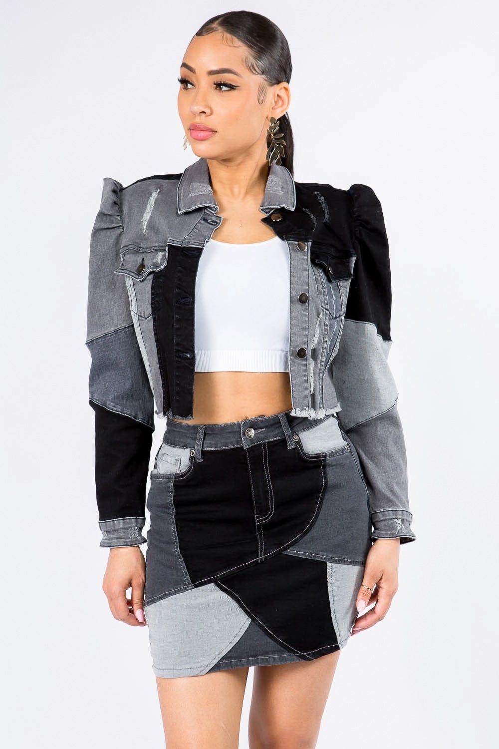 ront view of the Unique Kulture American Bazi Button Up Cropped Patchwork Denim Jacket, featuring a stylish cropped length, distinctive patchwork design, frayed edge hem, and puff shoulder trims. The jacket showcases a button front closure, perfect for adding a trendy and eye-catching element to any outfit.
