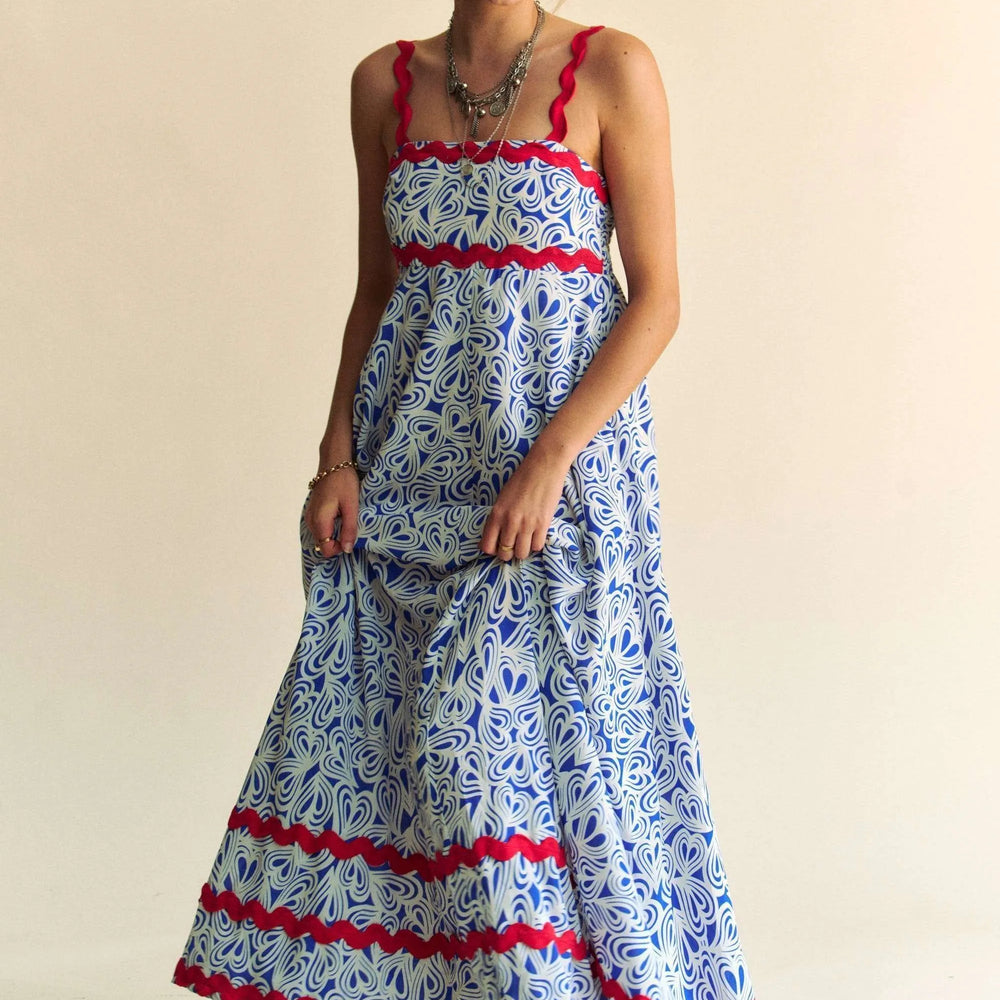 Make a statement with Unique Kulture’s Geo Two-Tone Printed Tiered Maxi Dress with Wavi Trim. This eye-catching maxi dress features a bold geometric two-tone print and playful Wavi trim accents for a touch of boho chic. The tiered silhouette creates beautiful movement, while the slightly stretchy, smocked bodice ensures a flattering and comfortable fit. Crafted from lightweight, breathable polyester, this dress is perfect for special occasions, summer parties, or any day you want to stand out in effortless 