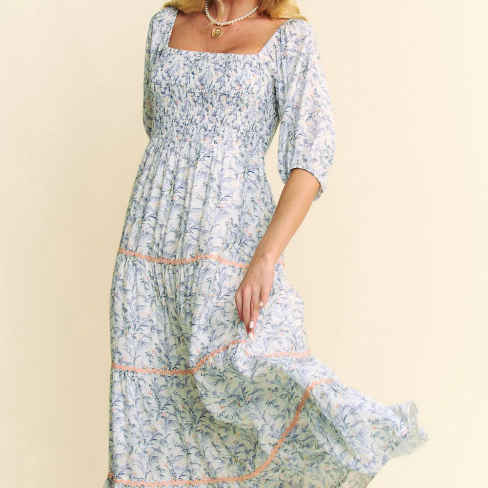 Model wearing a contrast ric smocked bodice tiered midi dress from Unique Kulture, featuring a textured bodice and flowy tiered skirt.

 side view