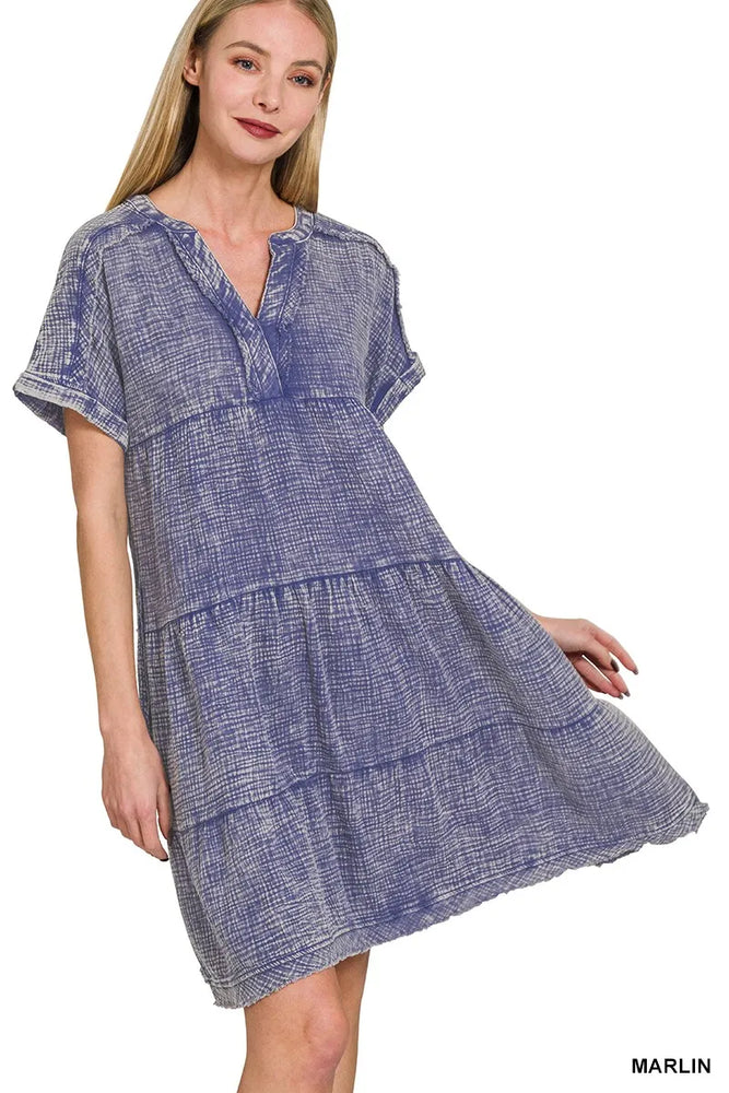 Model wearing a washed double gauze raw edge V-neck dress from Unique Kulture, featuring a relaxed tiered silhouette, exposed seams, and pockets.

