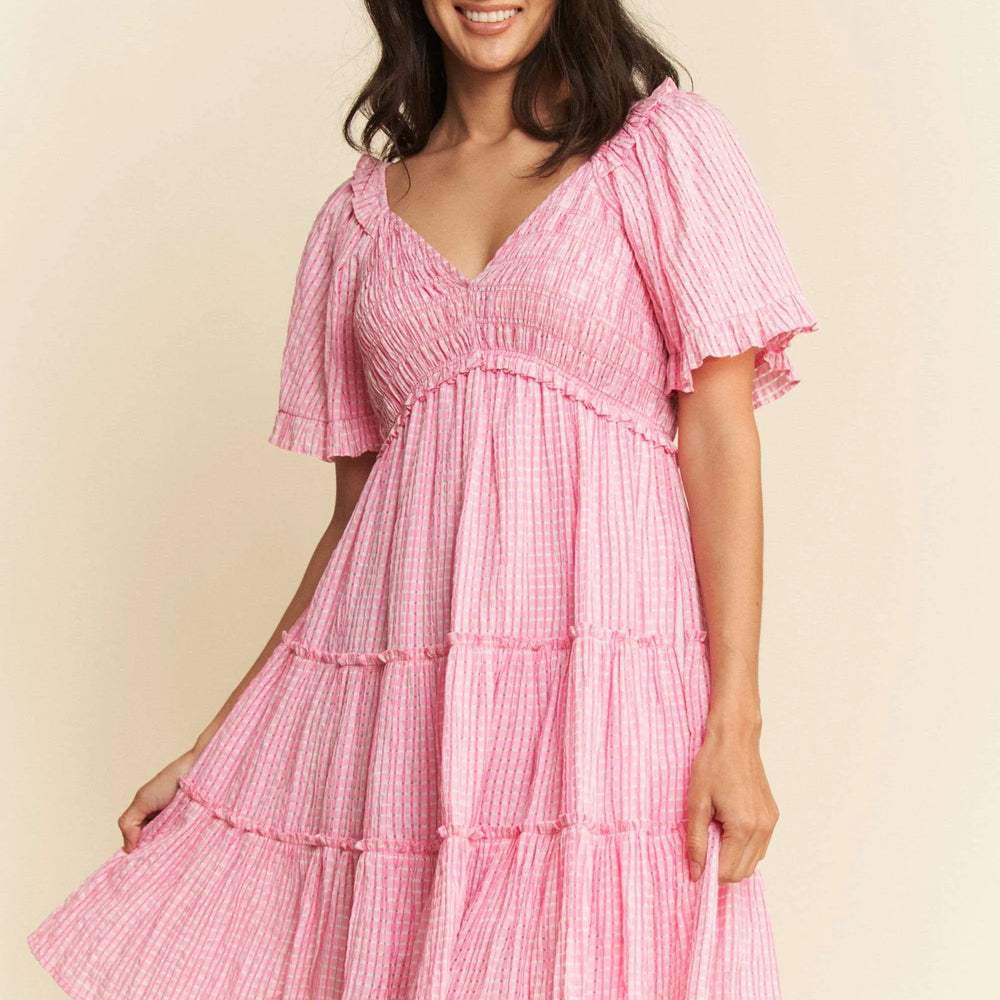 Model wearing a jacquard checker smocked tiered dress from Unique Kulture, featuring a textured pattern, smocked top, and flowy tiered silhouette.

