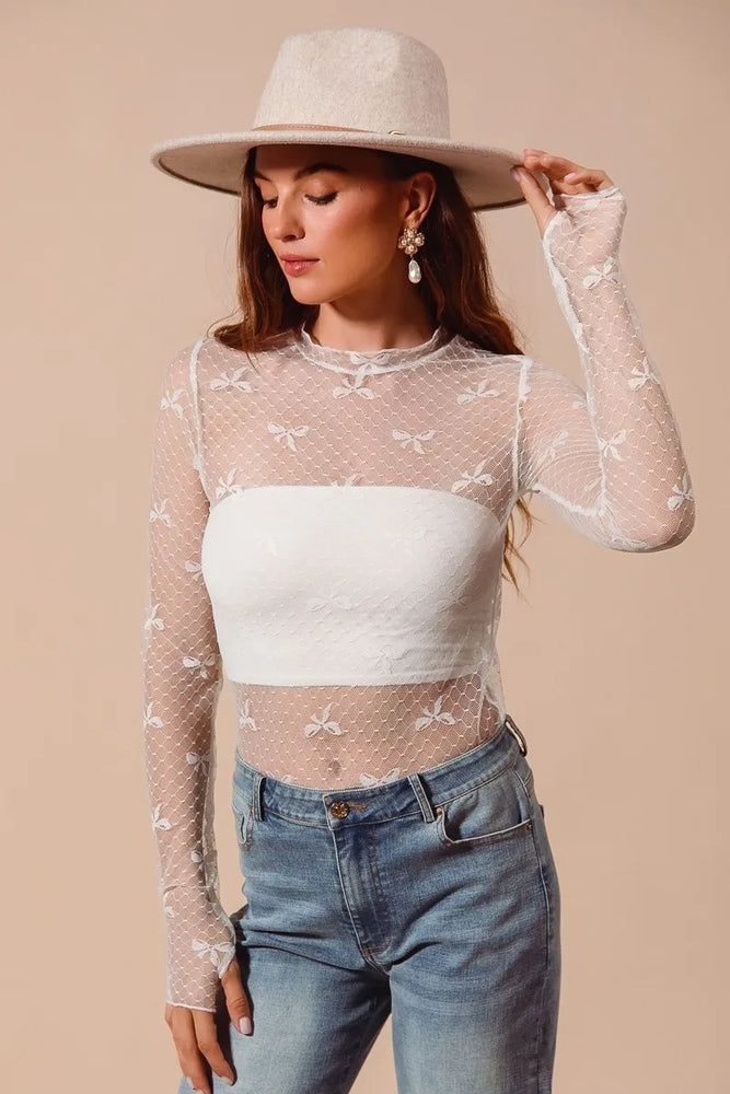 Sheer mesh lace top with bow ribbon pattern and floral embroidery, long sleeves, fitted silhouette, and crew neckline—styled for romantic and elegant layering.

