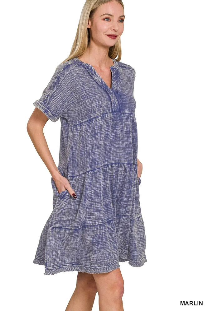 Model wearing a washed double gauze raw edge V-neck dress from Unique Kulture, featuring a relaxed tiered silhouette, exposed seams, and pockets.

 side view
