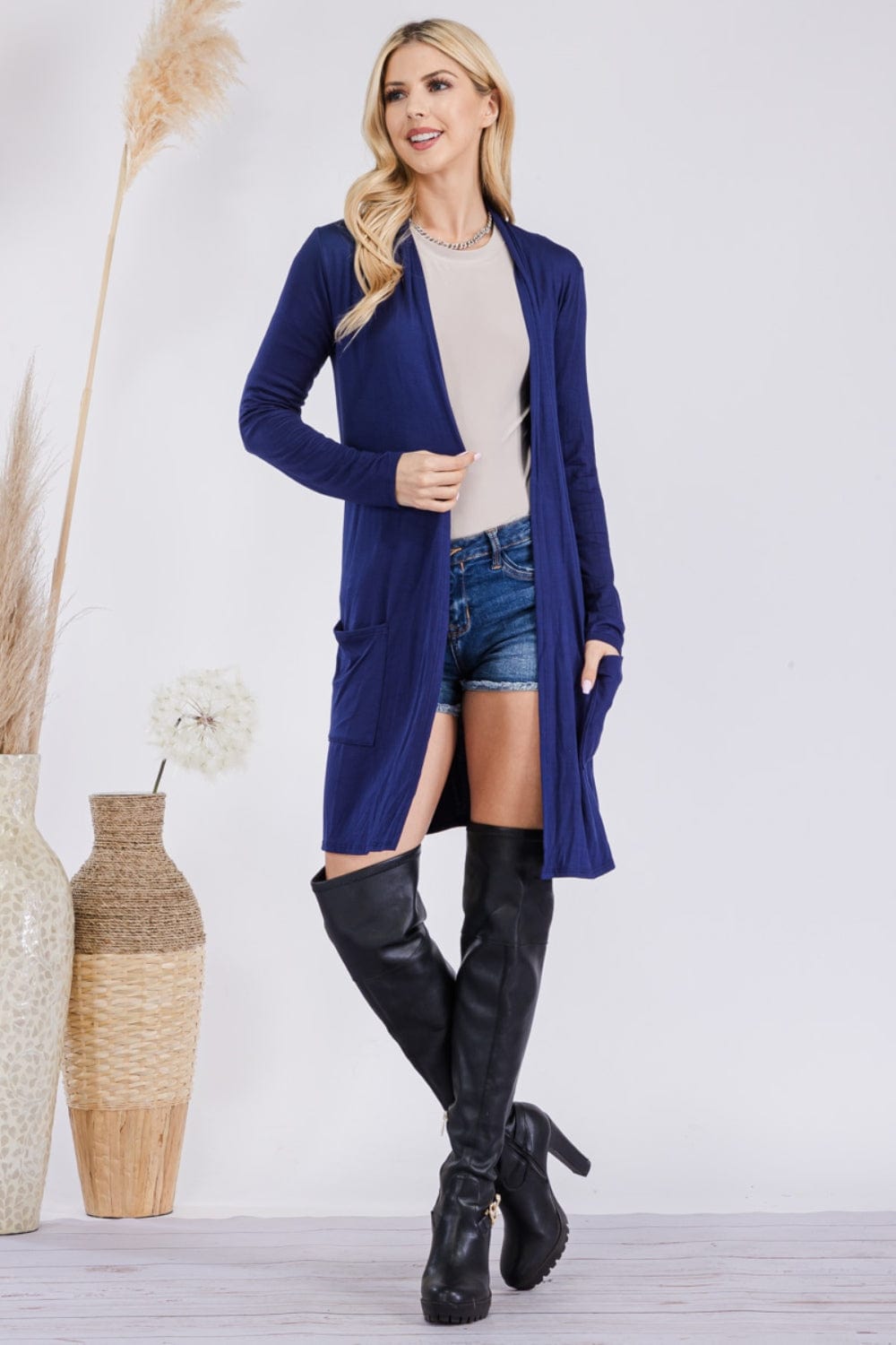  Celeste Full Size Open Front Cardigan with Pockets, featuring a stylish and versatile open-front design in a solid color. The cardigan is made from a highly stretchy fabric blend, showcasing its comfortable fit and functional pockets, perfect for layering over various outfits.
