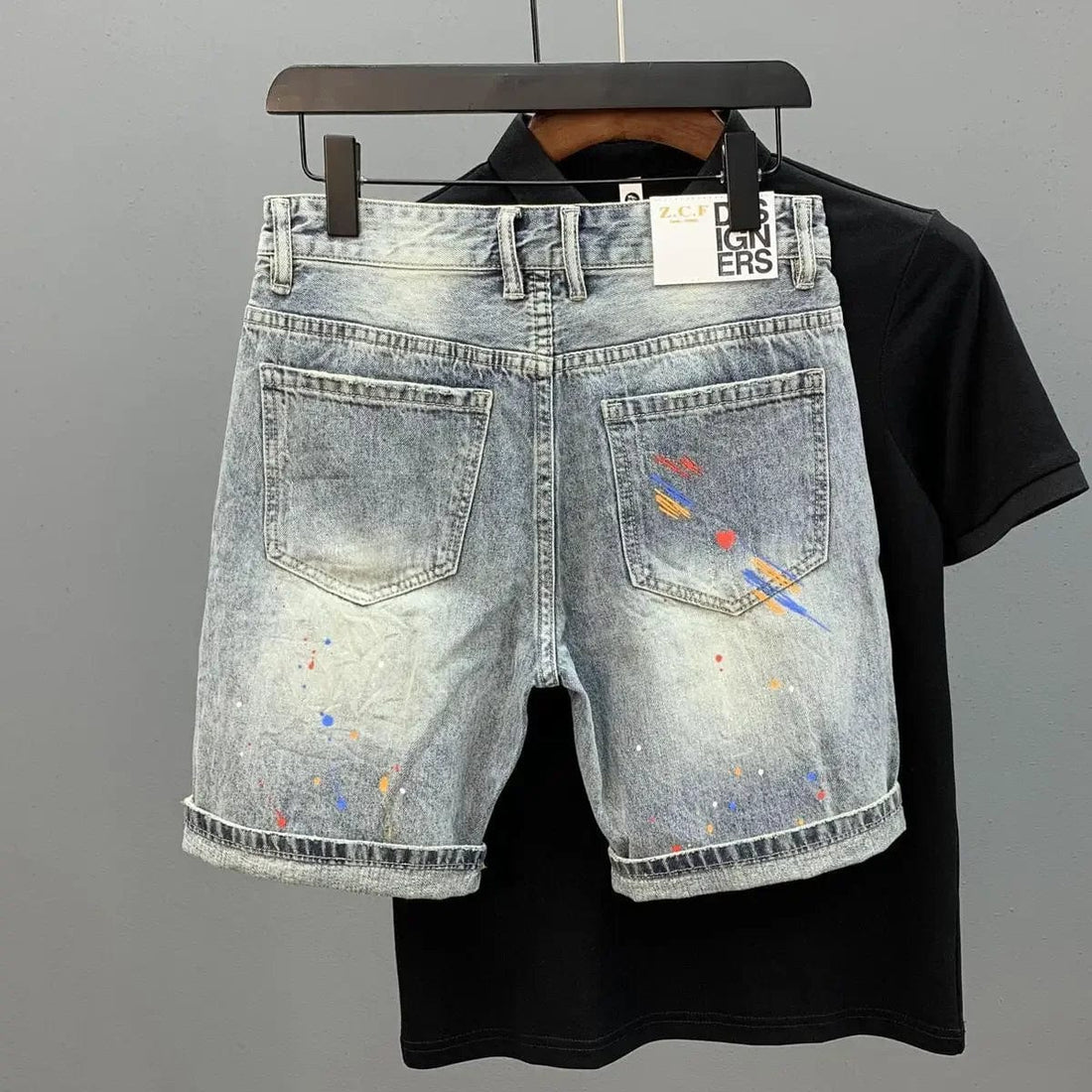 A pair of Unique Kulture Claw Monkey Designer Jean Shorts displayed against a plain background. The shorts are made from high-quality denim, featuring a stylish distressed look with intricate stitching. A unique claw monkey graphic is prominently displayed, adding a bold and playful touch. The shorts have a modern, tailored fit with front and back pockets, and a button and zip closure.