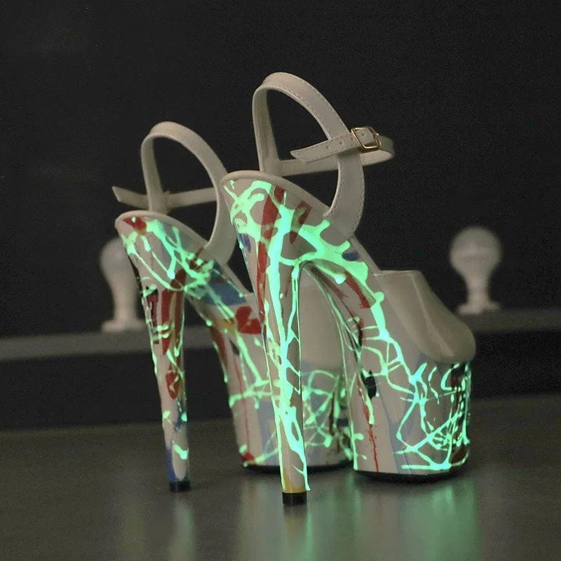 A pair of Lit Stiletto Designer Heels with thin, high heels and platform heights ranging from 5cm to 10cm. The sandals feature a peep-toe design, glossy patent leather upper, and open sides. They have front and rear straps for support and adjustable buckle closures. The heels are adorned with built-in lights that create a glowing effect. The solid color and sleek design give them a modern, punk-inspired look. The insole and lining are made of bonded leather, providing comfort and durability.