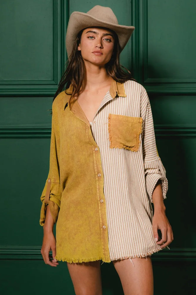 Model wearing a washed raw hem oversized shirt from Unique Kulture, featuring distressed fabric, buttoned front, and pocket details.

