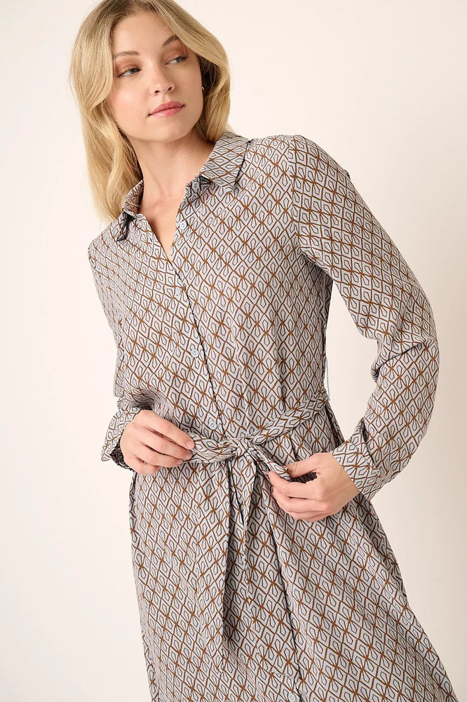 Model wearing an abstract print waist tie midi shirt dress from Unique Kulture, featuring a buttoned front, collared neckline, and a bold, modern print.


