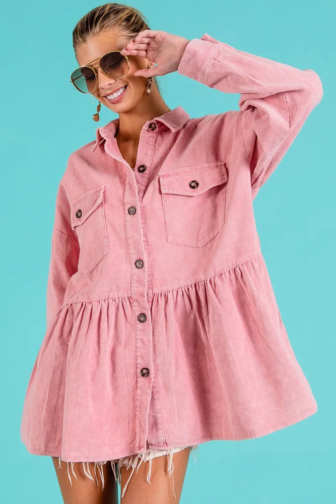 Woman wearing an eco-friendly corduroy ruffle peplum button-up shirt from Unique Kulture, featuring a feminine hem and front pocket. Pink version