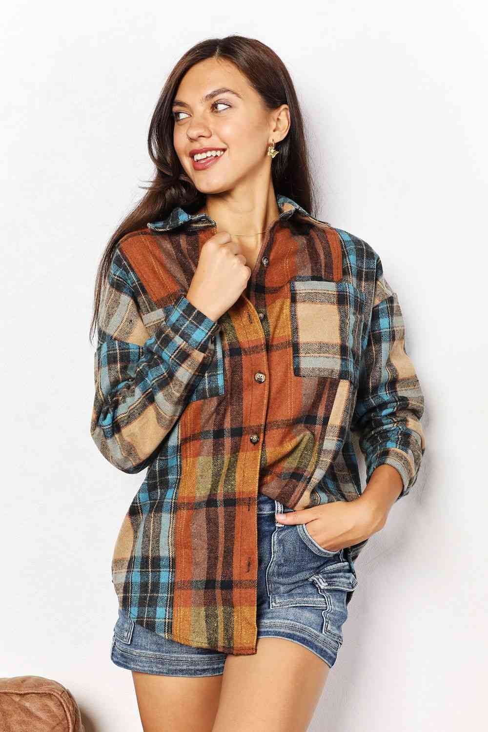 "Image: A stylish Double Take Plaid Curved Hem Shirt Jacket featuring breast pockets. The jacket showcases a classic plaid pattern, with a curved hem design for a modern and fashionable look. The breast pockets add functional detail, combining comfort and style seamlessly."