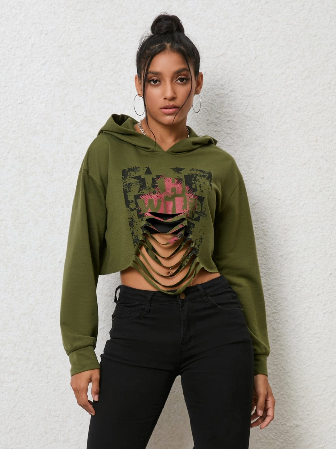 "Image: A model wearing the Unique Kulturre Cutout Long Sleeve Hoodie. The hoodie is black with a relaxed fit and features cutout details on the sleeves and a hood. The model is standing against a plain background, showcasing the hoodie's stylish design."